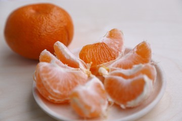 Fototapeta na wymiar many pieces of mandarin orange on the plate and one mandarin fruit