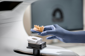 Dental technician placing jaw model into the 3d scanner at the laboratory, close-up