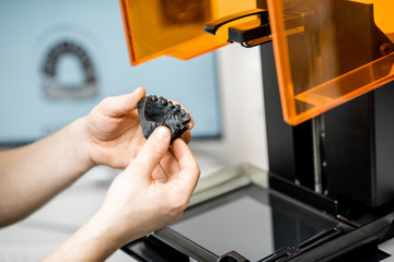 Dental technician removing jaw model from a 3d printer at the laboratory, modeling frame for implant production