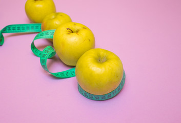 apple and centimeter tape on a colored background with a place for inserting the text. concept diet, healthy eating, sports.