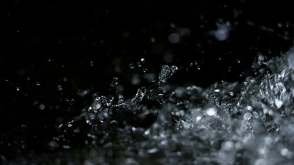 High speed blurry images of water splashing on black color background which represent concept of...