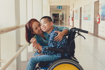 Mother and Asian special child on wheelchair is smile happily on background in school corridor, Life in the education age of disabled children, Happy disabled kid concept..