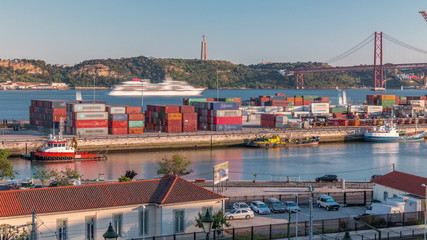 Skyline over Lisbon commercial port timelapse, 25th April Bridge, containers on pier with freight cranes