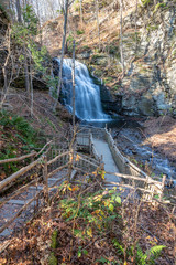Winding wooden boardwalk and stairs leading to a flowing river and small waterfalls. Bushkill Falls, Pennsylvania 