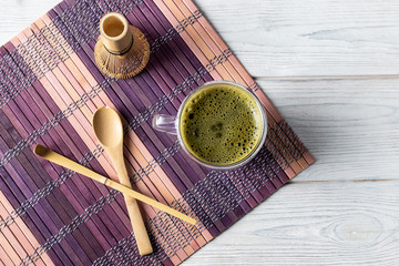 Green matcha tea drink and accessories on a white wooden background. Japanese tea ceremony concept.