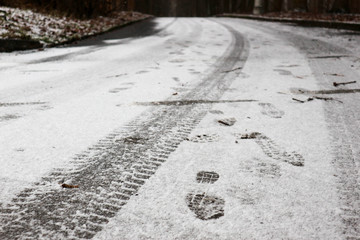 tire tracks and footprints in the first snow on the asphalt