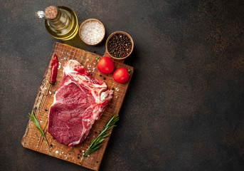 one raw steak with spices and rosemary on a stone background with copy space for your text