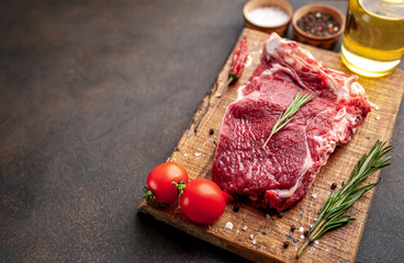 one raw steak with spices and rosemary on a stone background with copy space for your text