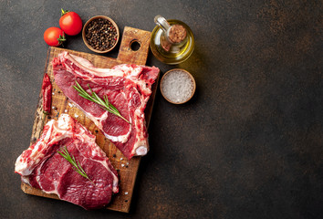 raw beef steaks with spices and rosemary on a stone background with copy space for your text