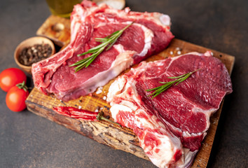 raw beef steaks with spices and rosemary on a stone background