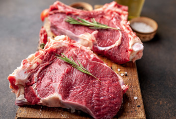 raw beef steaks with spices and rosemary on a stone background