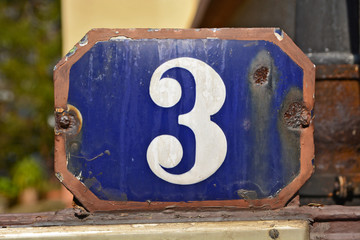 A house number plaque, showing the number three (3)
