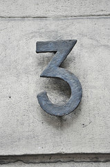 A house number plaque, showing the number three (3)