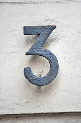 A house number plaque, showing the number three (3)