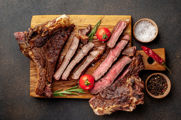two grilled steaks with spices, with two types of frying on a stone background