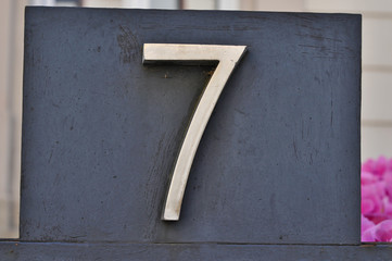 A house number plaque, showing the number seven (7)