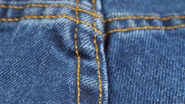 Seam on denim jeans, low angle. Shallow DOF. Close up, macro. Denim textile tracking. Slider shot