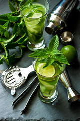 Mojito cocktail with lime and mint in  glass on black tray