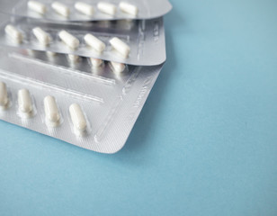 Medical pills in white on blue background. Pills in a plastic package. Healthcare and medicine concept. Top view, copy space, place for text