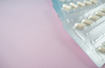 Medical pills in white on pink background. Pills in a plastic package. Healthcare and medicine...