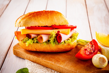 Tasty sandwich with meat and vegetables on wooden table