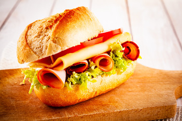 Tasty sandwich with meat and vegetables on wooden table