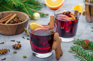 Mulled wine in a glass with orange, apple, raisins, cinnamon, star anise and other spices on a gray...