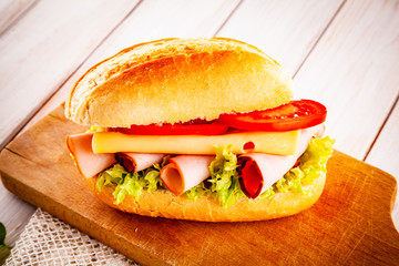 Tasty sandwich with meat and vegetables on wooden table