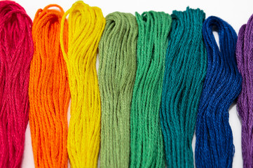 Colored threads for embroidery, seven colors of the rainbow lie in a row on a white background