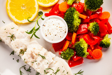 Fish dish - fried fish fillet with vegetables on white background