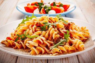 Fusilli with sausages and vegetables on wooden table