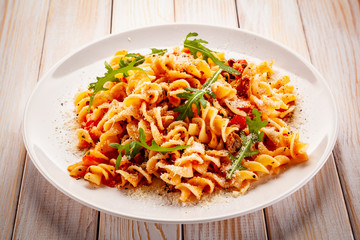 Fusilli with sausages and vegetables on wooden table