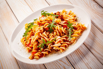 Fusilli with sausages and vegetables on wooden table