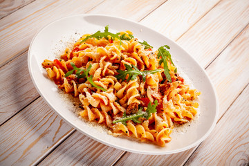 Fusilli with sausages and vegetables on wooden table