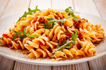 Fusilli with sausages and vegetables on wooden table