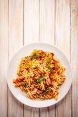 Fusilli with sausages and vegetables on wooden table