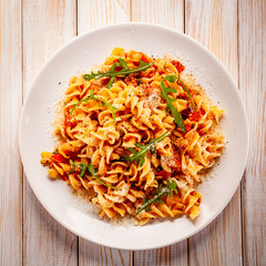 Fusilli with sausages and vegetables on wooden table