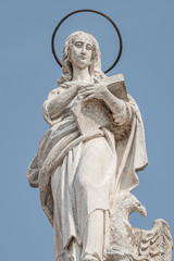 Fototapeta premium Ancient aged sculpture of beautiful Holy Maria at roof of Santa Maria Assunta Jesuits Church in Venice, Italy, details, closeup
