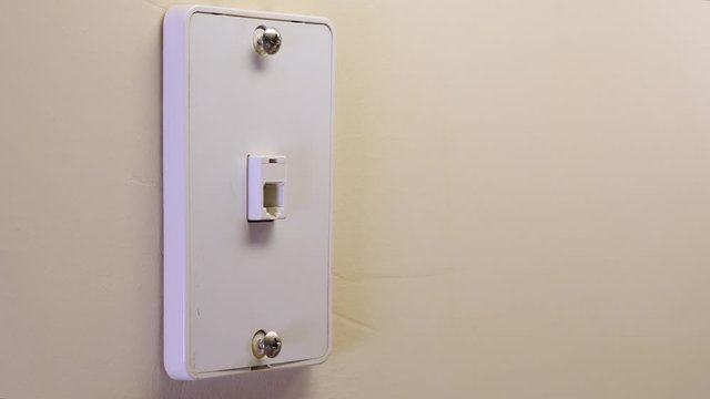 Male electrician unplugging landline telephone cord from wall mounted jack plate.