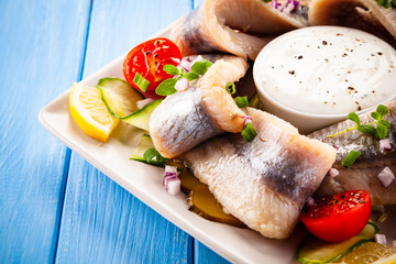 Marinated herring fillets on wooden table