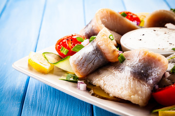 Marinated herring fillets on wooden table