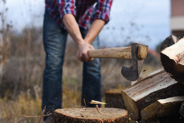 Lumberjack chopping wood for winter, Young man chopping woods with an axe