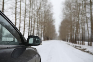 Car on a snowy winter road in fields.