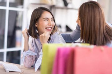 A beautiful Asian woman has made a purchase online and is glad that the computer screen.