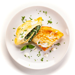 Crepes with spinach and feta cheese on white background