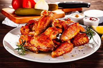 Barbecued chicken wings with french fries and vegetable salad on timber