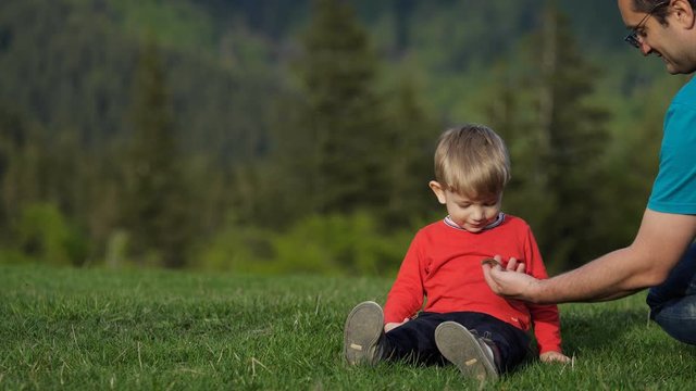 Man showing lizard to kid in nature