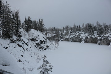 Snow covered rocks with deep grottoes around the frozen lake