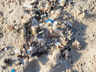 Environmental pollution. Sand beaches polluted with pieces of plastic waste. Micro plastics debris on the beach. Pieces of plastic residues