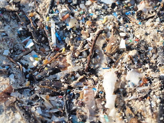Environmental pollution. Sand beaches polluted with pieces of plastic waste. Micro plastics debris on the beach. Pieces of plastic residues